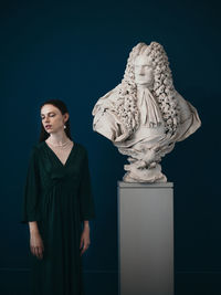 Portrait of young woman standing against wall