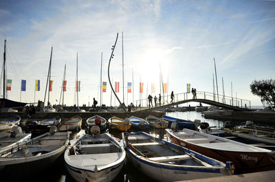 Sailboats moored at harbor against sky