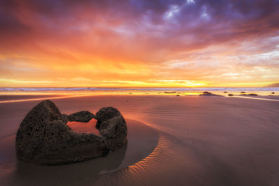 Heart shape on beach against sky during sunset