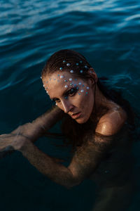 Young woman with golden skin in water portrait