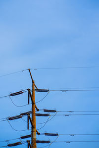 Low angle view of electricity pylon against blue sky