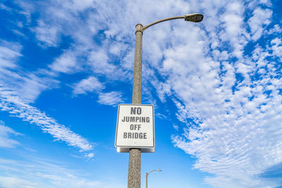 Low angle view of road sign against blue sky