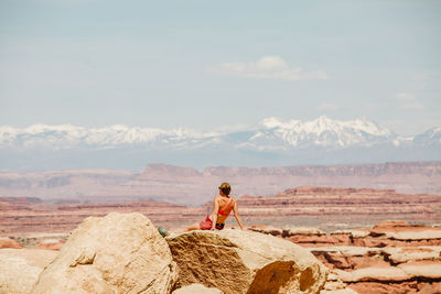 Female hiker in sports bra relaxes at a viewpoint in the maze utah