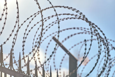 Low angle view of barbed wire against sky