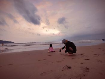 People on beach against sky during sunset