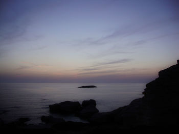 Rocks in sea at sunset