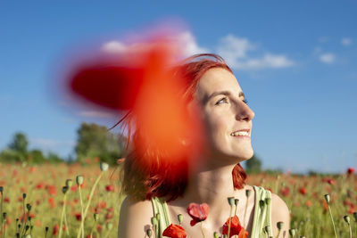 Portrait of young woman standing against sky