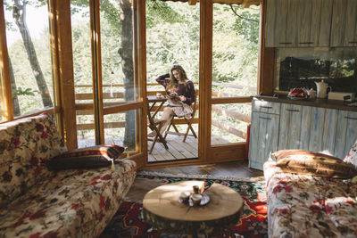 Young woman reading newspapers on tree house balcony