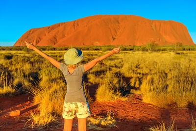 Rear view of woman standing on land against sky