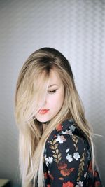 Side view of beautiful woman with blond hair against wall