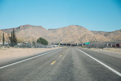 Road in desert against clear blue sky