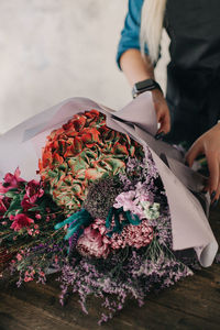 Girl in a black apron makes a bouquet to order