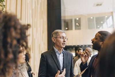 Senior businessman discussing with male delegate during networking event at convention center