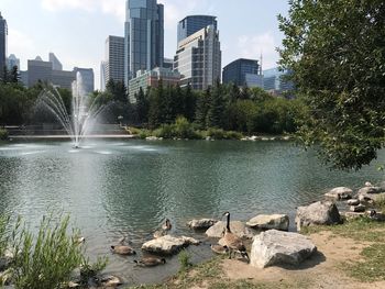 Fountain by river in city against sky