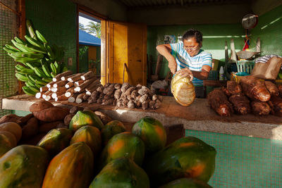 Woman cuts vegetables at her fish market stall at sunrise in los cocos porlamar, margarita venezuela