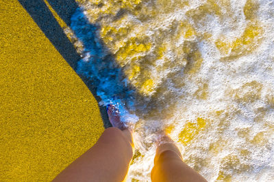 Low section of woman walking yellow water