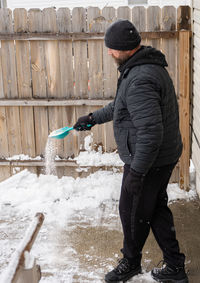 Man spreads rock salt to melt the ice and snow on your walkway