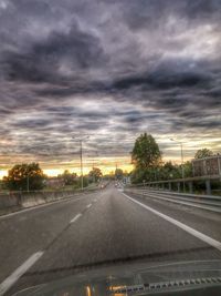 Cars on road against cloudy sky