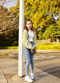 Portrait of smiling young woman standing on road