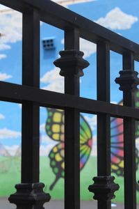 Close-up of metal railing by building against sky