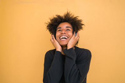 Portrait of smiling young woman against yellow background