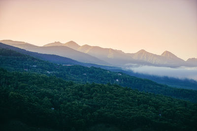 Scenic view of tree mountains against clear sky during sunset