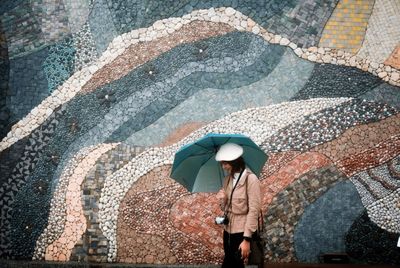 Man with umbrella walking on street during rainy season