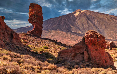 Rock formations on landscape against cloudy sky