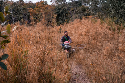 Man riding motor scooter amidst meadow