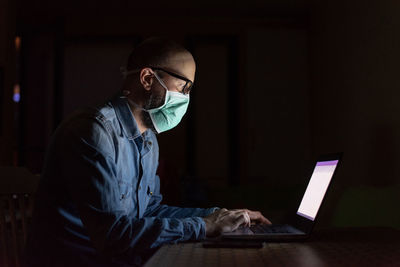 Side view of man using laptop at home