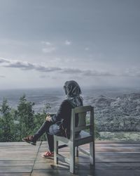 Rear view of woman sitting on bench