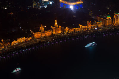 Illuminated buildings by river at night