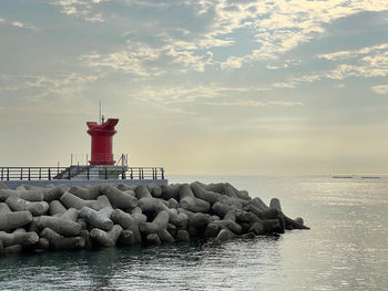 Lighthouse by sea against sky