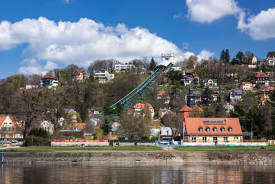 City by river and buildings against sky