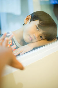 Side view of cute baby boy looking through window