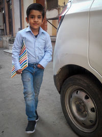 Portrait of boy standing by car