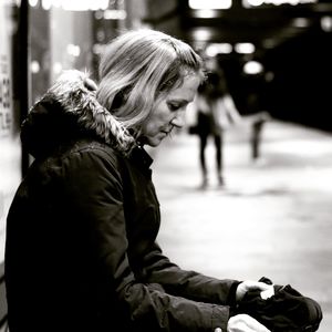 Side view of woman wearing warm clothing while sitting outdoors