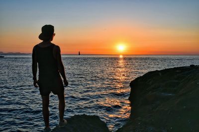 Man looking at sea against sky during sunset