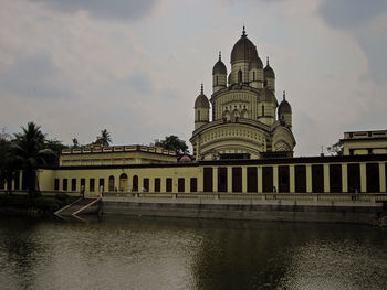 View of building by river against sky in city