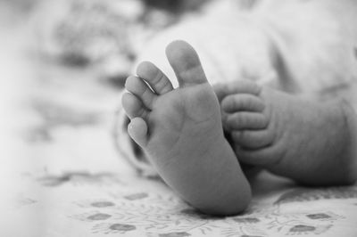 Low section of baby lying on bed at home