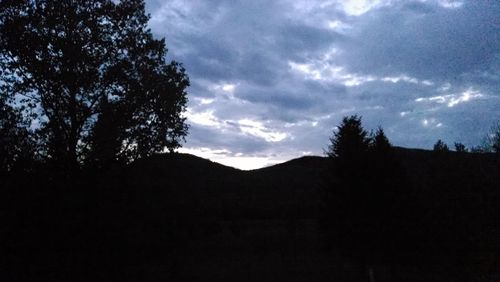 Silhouette of trees against cloudy sky