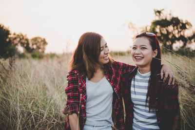 Happy friends standing on land against sky