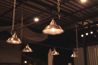 Low angle view of illuminated light bulb hanging from ceiling