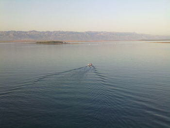 Man in boat sailing on lake against sky