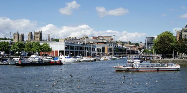 Boats moored at harbor against sky in city