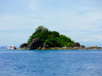 Ferry boat by island in sea against sky