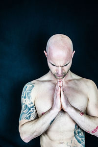 Close-up portrait of shirtless man against black background