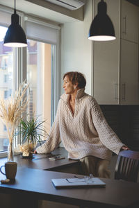 Side view of young woman using laptop while sitting at home