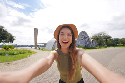 Portrait of young woman standing against sky