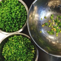 High angle view of green peas in utensils on table at kitchen